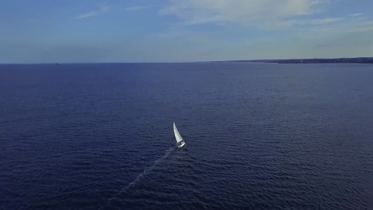 Aerial footage of a white sailing boat in an empty ocean in the North Sea on a hot summers day.