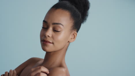 portrait healthy young woman touching face with hand caressing smooth skin complexion enjoying soft natural beauty on blue background skincare concept