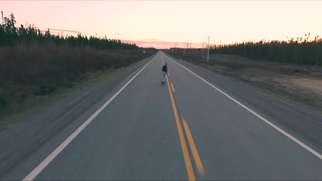 a young boy do skateboard in the middle of a backroad in canada