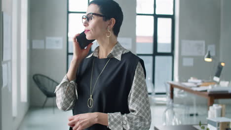 elegante mujer de negocios de mediana edad hablando por teléfono en la oficina