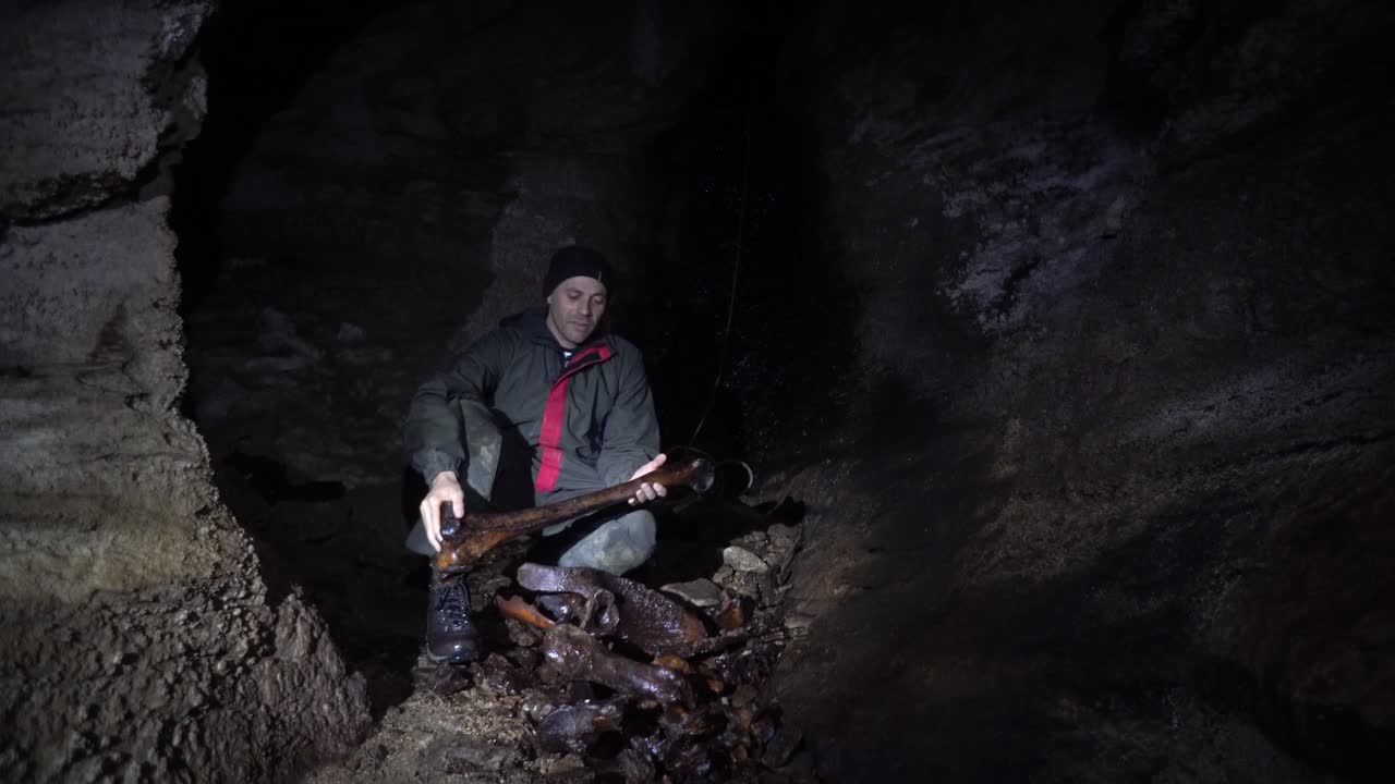 Caver displaying a large femur of the extinct giant moa bird that was found in a New Zealand cave