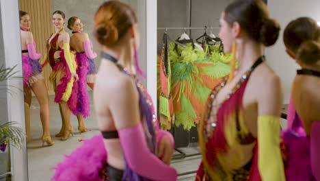 bellas damas mostrando sus movimientos frente a un espejo con vestidos de plumas