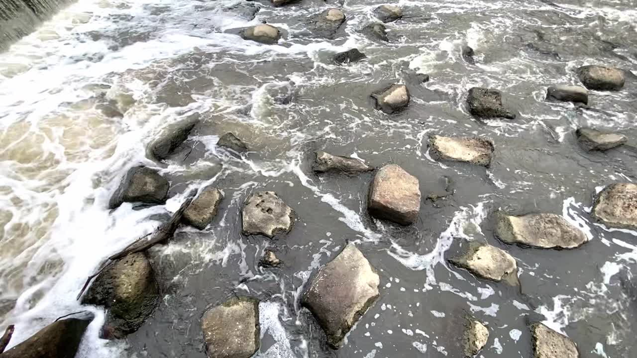 primer plano del agua del río barriendo y fluyendo a través de las rocas durante el día - toma estática