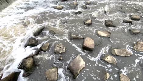 Primer-Plano-Del-Agua-Del-Río-Barriendo-Y-Fluyendo-A-Través-De-Las-Rocas-Durante-El-Día---Toma-Estática