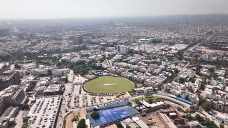 Luftaufnahme-Der-Stadt-Karatschi-Voller-Gebäude-Und-Häuser-Und-Eines-Cricketplatzes-Mitten-In-Der-Stadt