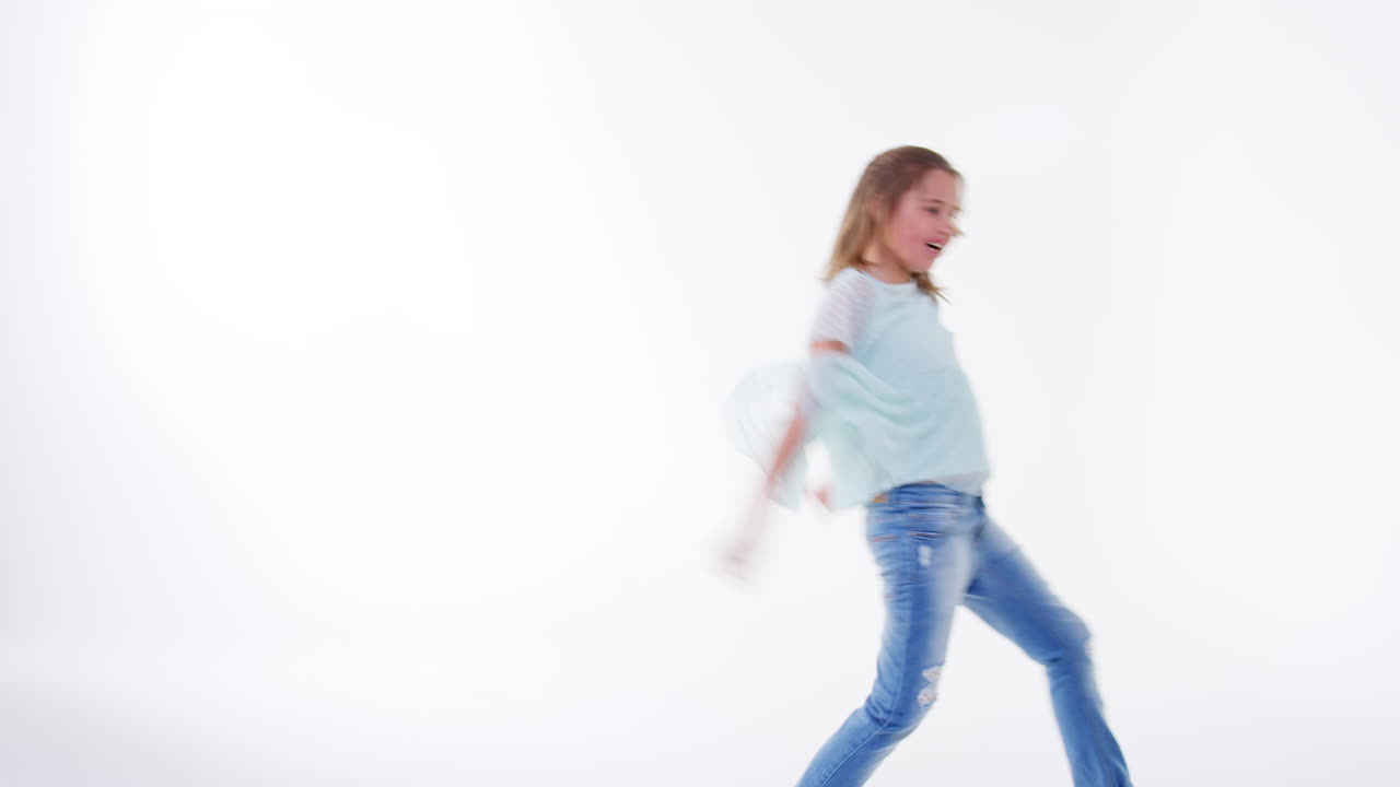 Ragazza giovane che corre e salta su sfondo bianco