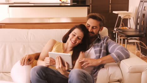 pareja relajándose en el sofá y usando una tableta digital