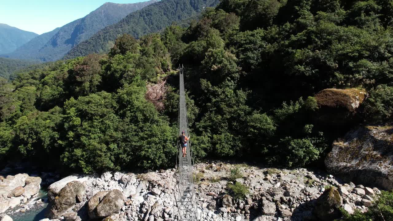 스 ⁇  브리지 에 있는 소녀 의 공중 크레인 이 원시적 인 자연 에서 강 을 건너고 있다