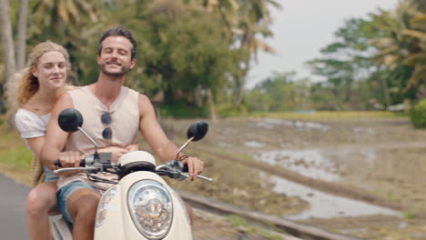 fun couple riding scooter on tropical island happy woman celebrating with arms raised enjoying vacation road trip with boyfriend on motorcycle ride