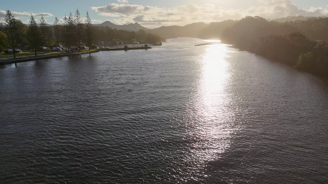 Drone captures serene sunset over Brunswick Heads river, highlighting calm waters and scenic landscape with warm, golden lighting