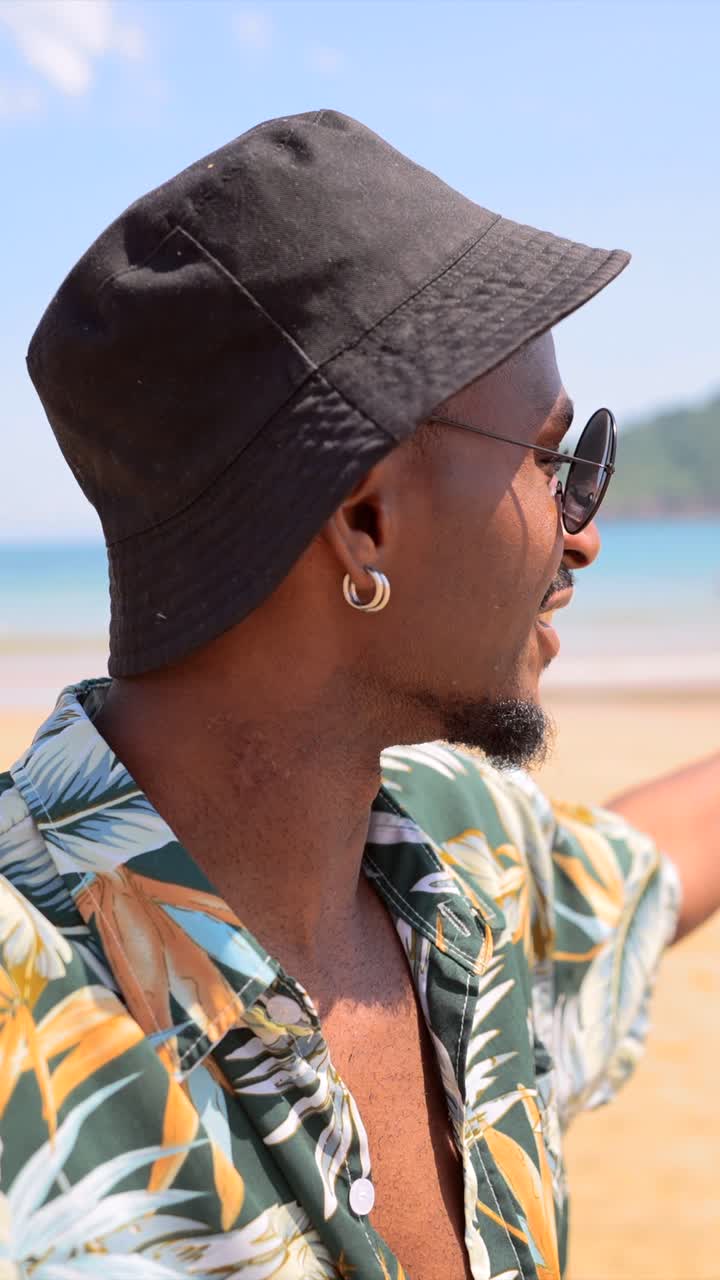 Man on a beach wearing sunglasses and a hat