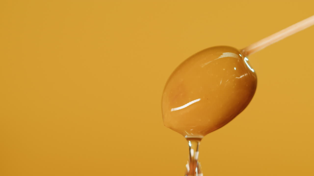 Close-up of a single olive on a toothpick with water droplets