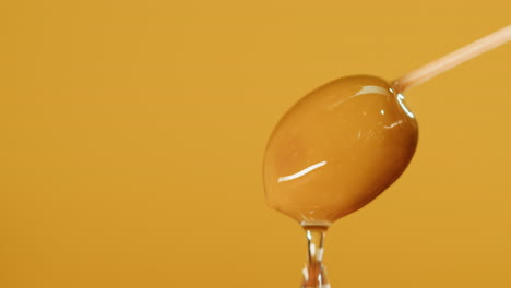 close-up of a single olive on a toothpick with water droplets