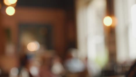 blurry video frames reveal a warmly lit indoor space, possibly a café or lounge, with indistinct figures and soft natural and artificial light