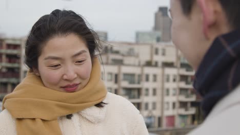 junges asiatisches paar mit romantischem mann, der einer frau vor der skyline der stadt einen heiratsantrag macht 4