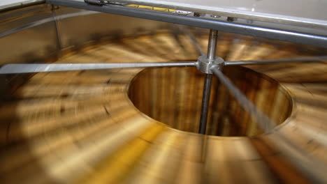 quick rotation of wooden honey frames in the centrifuge machine. electric equipment for honey harvesting at apiary.