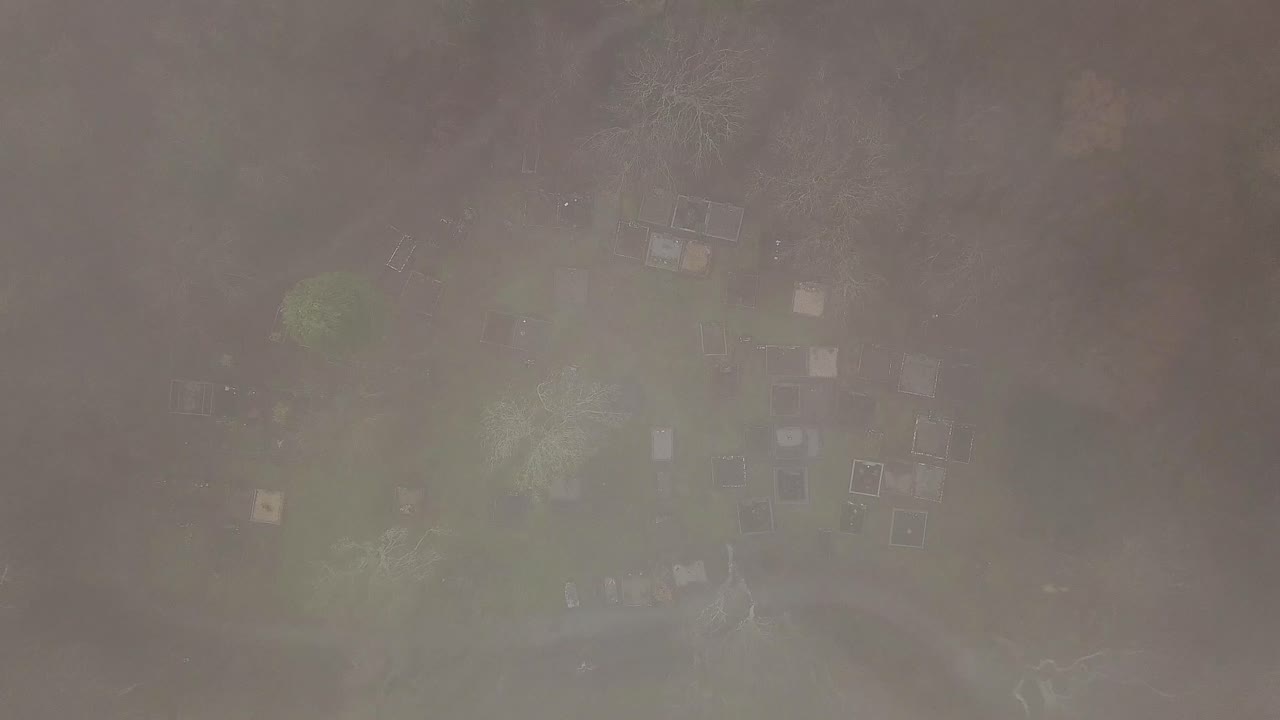 위에서 아래로 내려가는 항공기는  안개에서 사라지는 오래된 묘지에 내려갑니다.