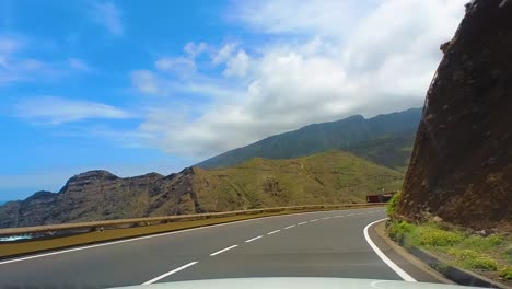 idyllic drive on a curvy empty mountain road, surrounded by tall green mountains, clear blue sky and the atlantic ocean, canary islands, la gomera, spain, europe