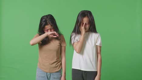얼굴과 팔에 이 있는 폭력의 희생자인 젊은 아시아 여성들이 스튜디오의 녹색 스크린 배경에서 울고 있습니다.