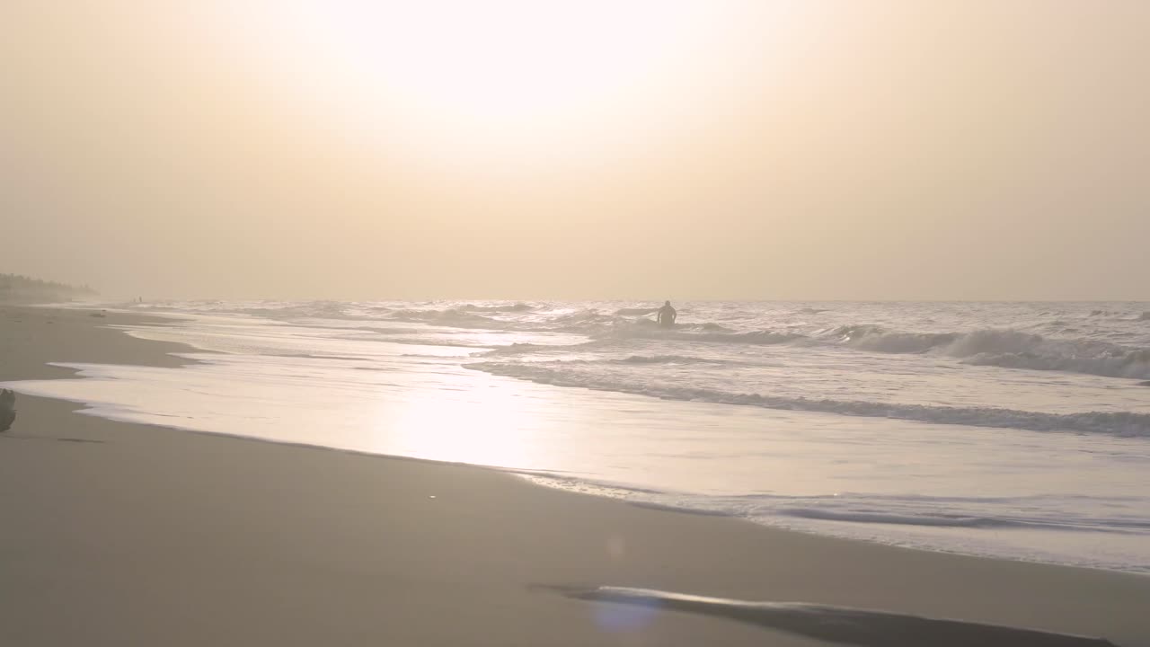 Obese person leaves the sea in the distance during a sunset