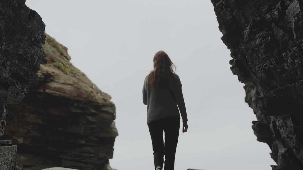 Silhouetted Woman Standing Between Dramatic Cliffs