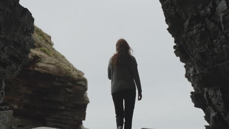 silhouetted woman standing between dramatic cliffs