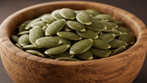 a close-up look at a beautifully crafted wooden bowl filled with smooth, green pumpkin seeds, showcasing their unique shape and texture