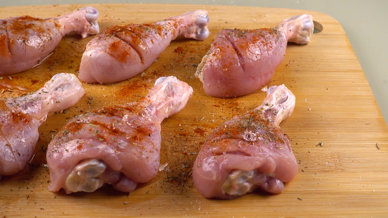 Cosce di pollo cosparse di olio d'oliva su un tagliere. Il processo di marinatura della carne
