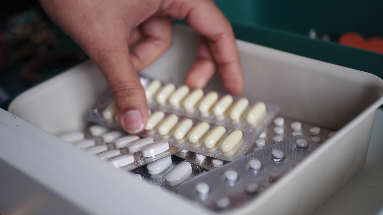 Hand Taking Blister Pack of Pills from Container