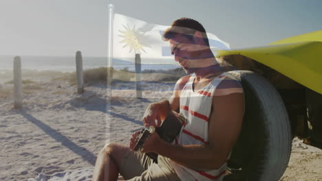 playing guitar on beach, man with uruguay flag animation in sunlight