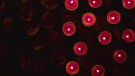 toma aérea de velas rojas románticas encendidas en el fondo cubiertas de pétalos de rosa con espacio de copia 1