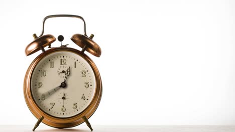 la aguja del reloj gira rápidamente el lapso de tiempo. la aguja el reloj gira rápido en el reloj de alarma de bronce vintage sobre fondo blanco.