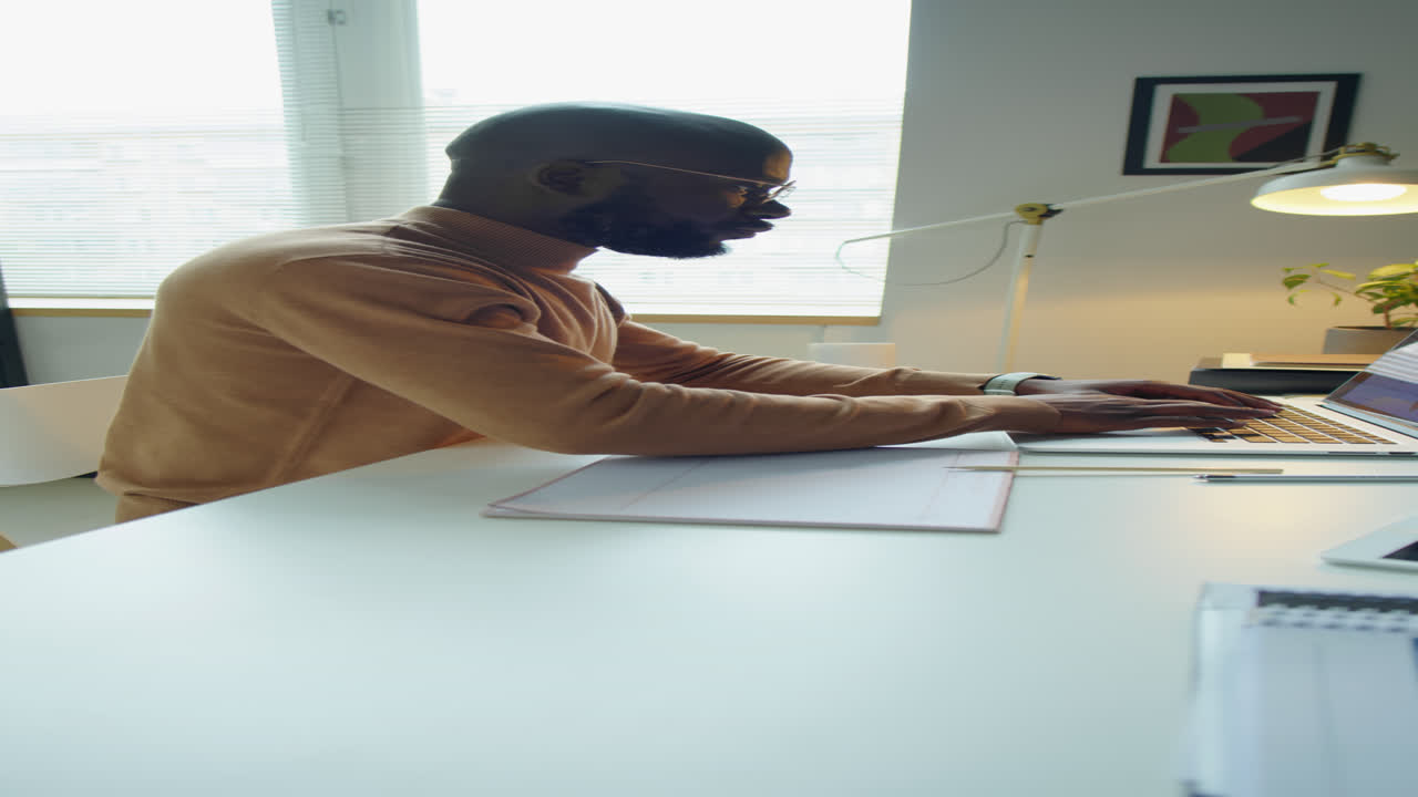 Black Businessman Using Laptop and Taking Notes in Office