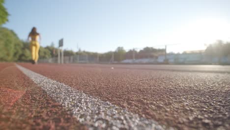 woman jogging on outdoor track in sportswear at athletic field