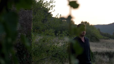 hombre con una camisa negra caminando a través de un campo de hierba durante el atardecer