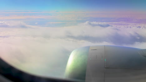 a view from an airplane window focusing on the jet engine, flying high above the clouds. the rainbow effect of the light on the engine adds a serene vibe