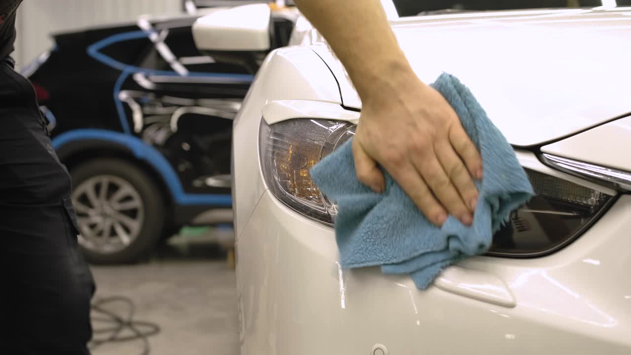 hombre cubriendo el coche con cinta de poliuretano de vinilo. películas para el coche. pegatina película protectora en el faro del coche