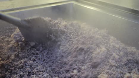 workers hands stirring red rice in a large pot in a catering food factory