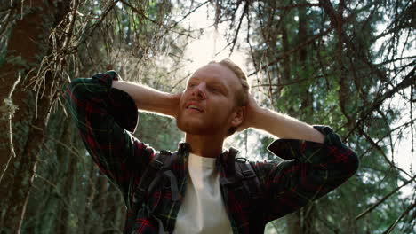 redhead man standing in green forest. handsome guy touching hair with hands