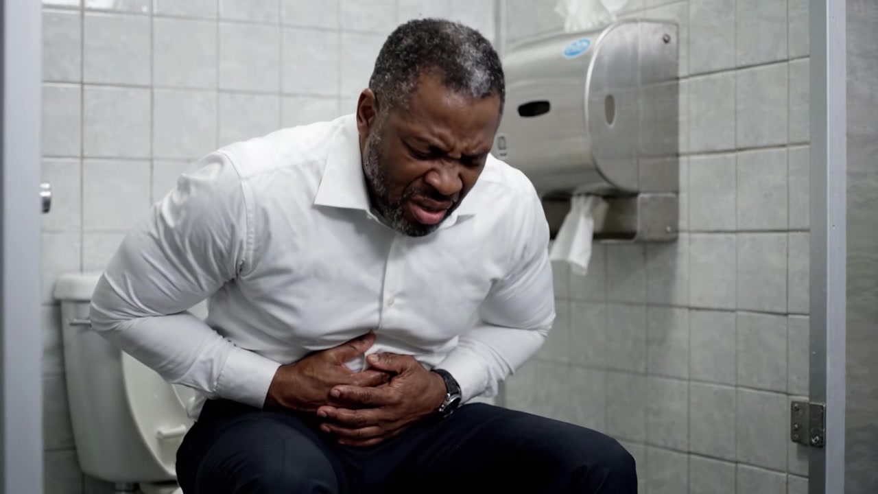 Frustrated man experiencing discomfort in a bathroom setting, showcasing the distress of an urgent situation while dealing with physical discomfort in a private space.