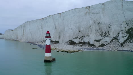 a circling aerial shot around beachy head lighthouse in east sussex with the tall white chalk cliffs near eastbourne