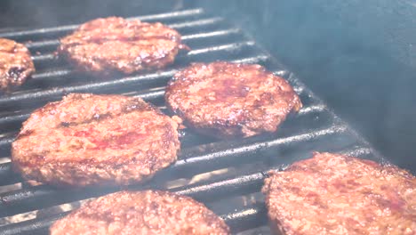 slider shot of burgers cooking on a public grill as fire flames up