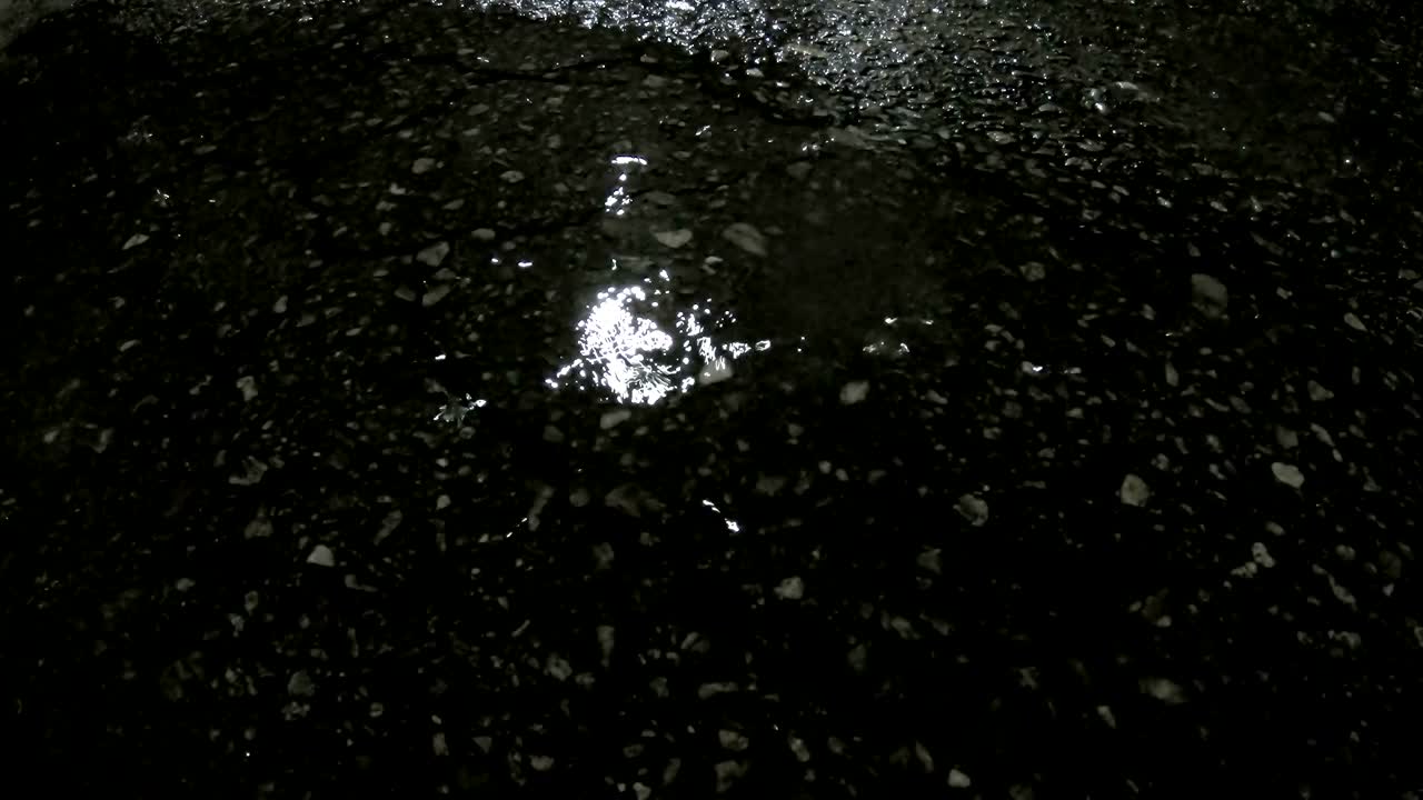 Cool chill wet raining season, concept with rain drops falling down the small street pond with reflection at night