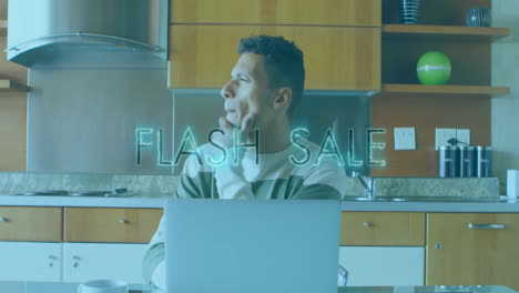 Man-working-on-laptop-in-kitchen-with-FLASH-SALE-animation-over-him