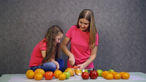 woman cutting fruits on table. young woman with daughter preparing healthy food