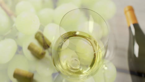 composite of glass of white wine over corks and white grapes on white background