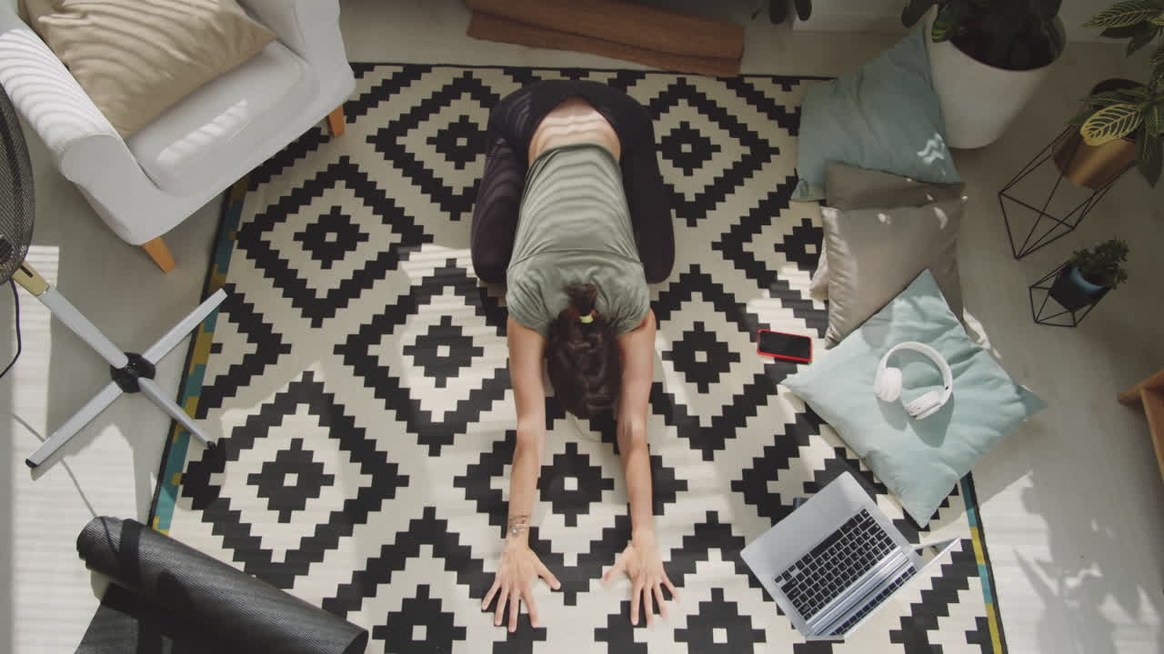 mujer practicando balasana durante una clase de yoga en línea en casa