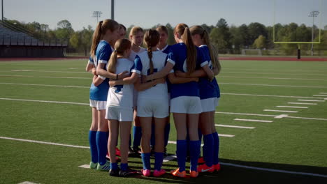 girls soccer team huddle on field