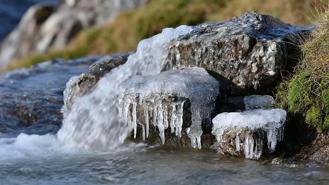 Frozen Stream Flowing Over Rocks, Showcasing Ice Formations and Water Interaction in a Serene Natural Landscape