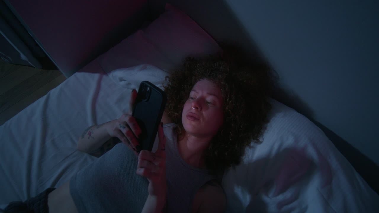 mujer usando el teléfono en la cama por la noche